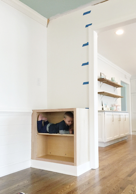 Base cabinet installed for built-in bookshelf with toddler inside