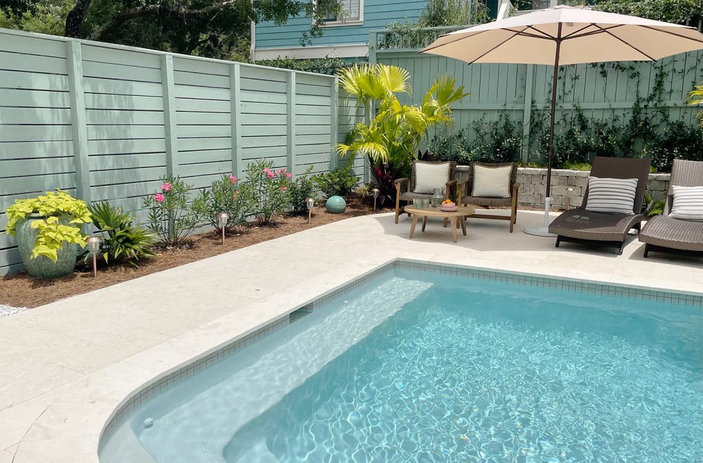 Two gray green painted wood fences surrounding pool at different heights